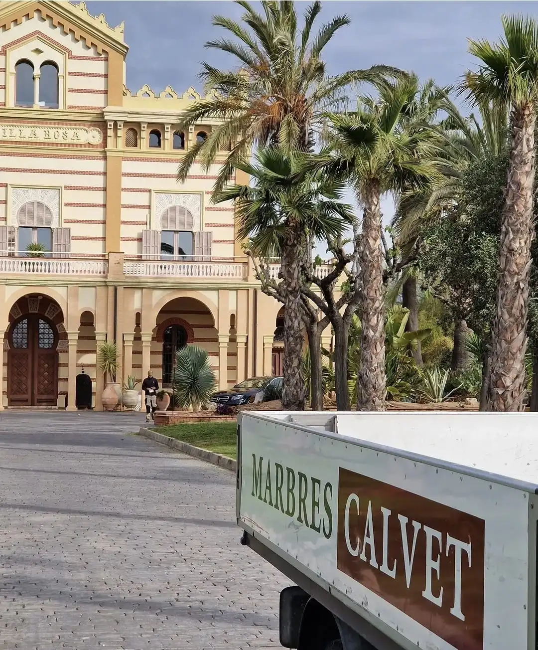 Camió de Marbres Calvet amb el rètol pintat, davant d’un edifici modernista