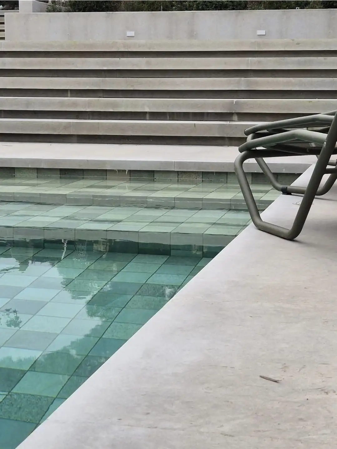 Detall de coronament de piscina en pedra clara amb gresite verd