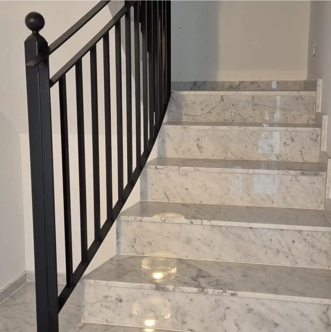 Escala de marbre de Carrara amb barana de ferro negre