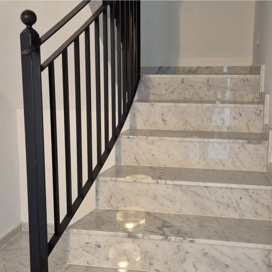 Escala de marbre de Carrara amb barana de ferro negre