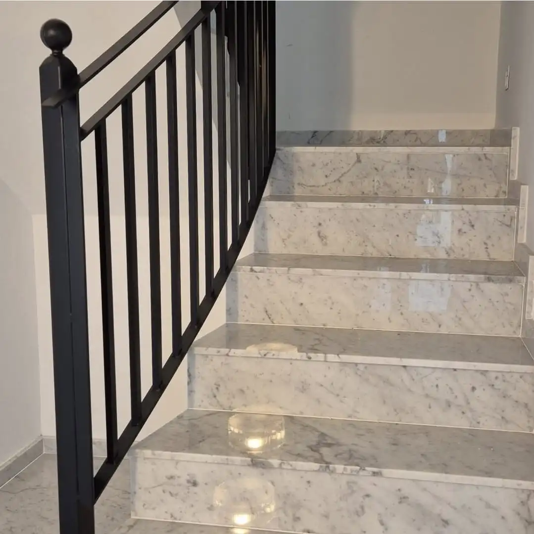 Escala de marbre de Carrara amb barana de ferro negre