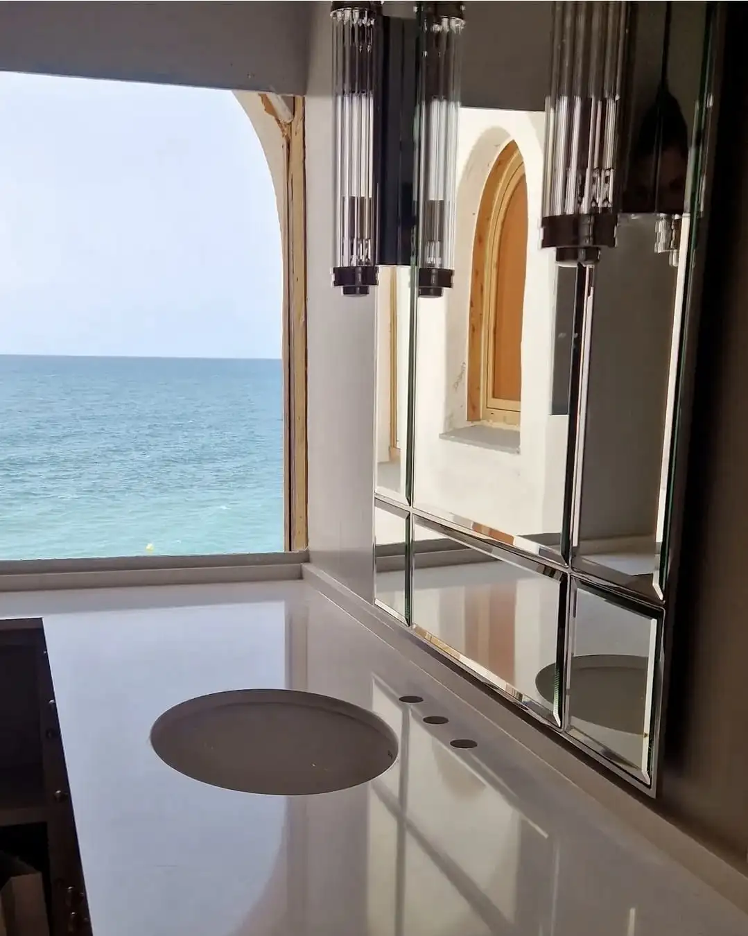 Taulell de lavabo blanc al costat d’una finestra amb vistes al mar